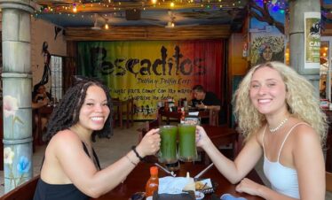 Two travelers toasting with chaya agua fresca during a Cancun Taco Tour