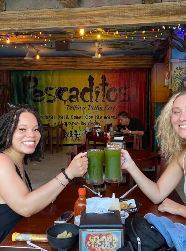 Two travelers toasting with chaya agua fresca during a Cancun Taco Tour