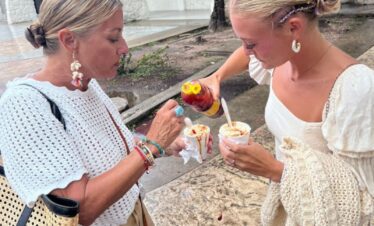 Two travelers preparing esquites Mexican street corn during a Cancun Taco Tour