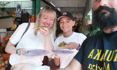 Guide sharing traditional tlacoyo with travelers at Mercado 23 Cancun food tour