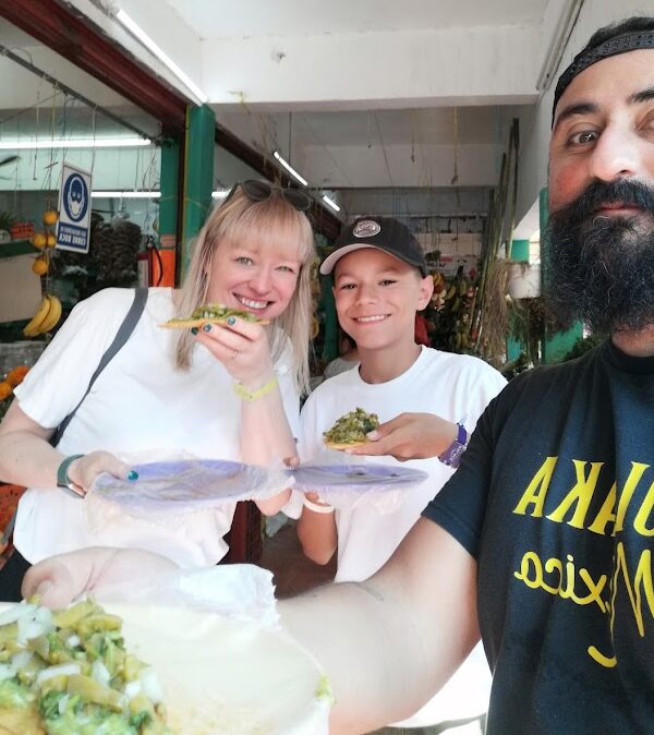 Guide sharing traditional tlacoyo with travelers at Mercado 23 Cancun food tour
