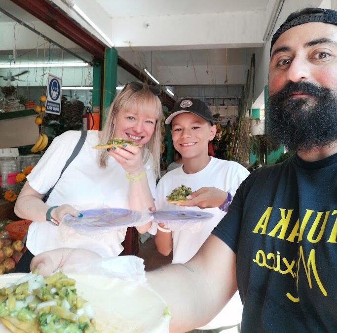 Guide sharing traditional tlacoyo with travelers at Mercado 23 Cancun food tour