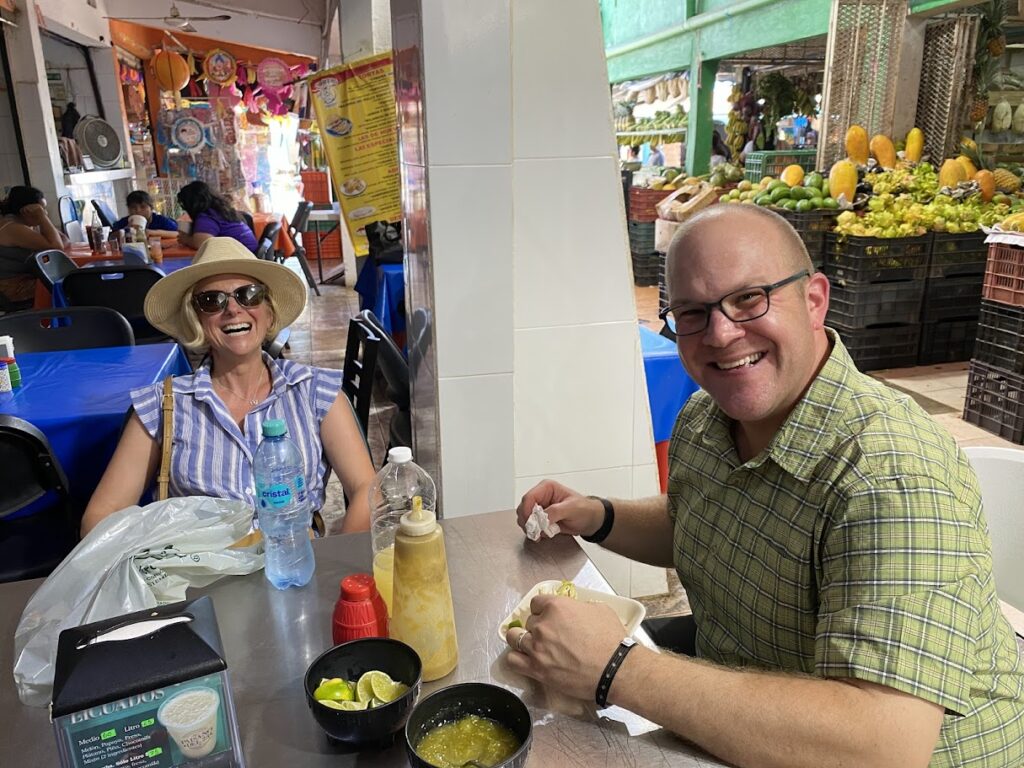 Couple enjoying traditional pork taco at Mercado 23 Cancun food market