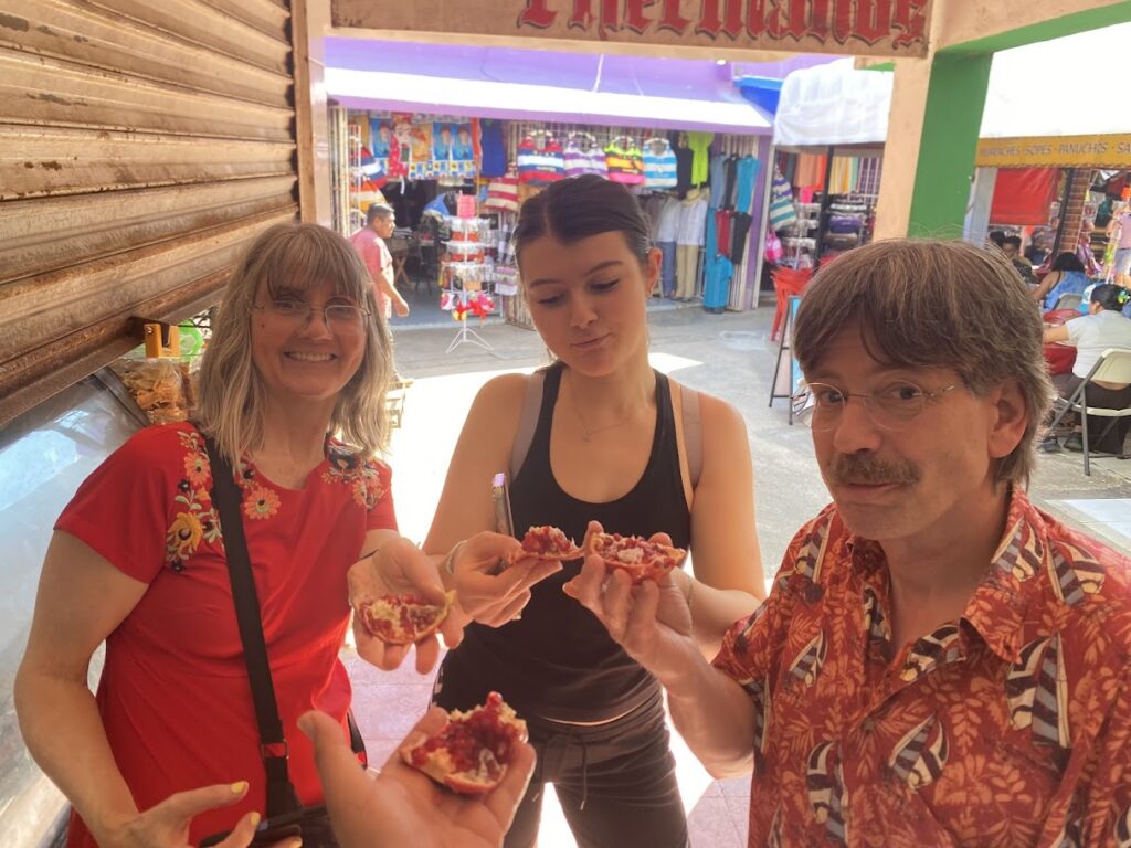 Family tasting fresh pomegranate at Mercado 23 local market in Cancun