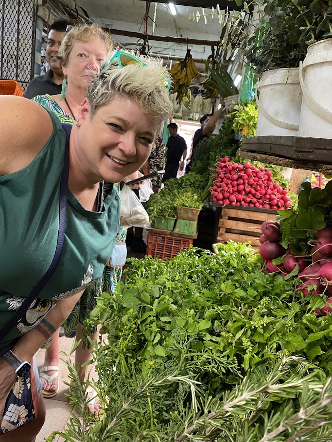 Traveler exploring fresh vegetables and aromatic herbs at Mercado 23 Cancun market