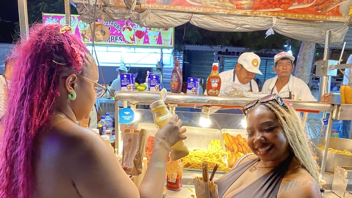 Two travelers enjoying fresh churros at the end of a Cancun Taco Tour