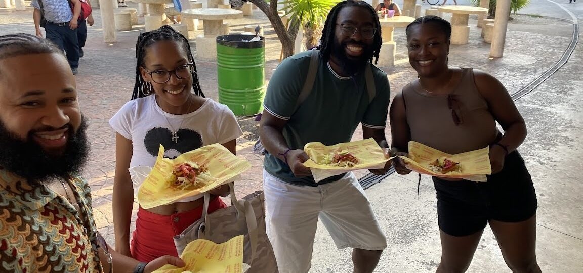 Travelers holding a plate of Yucatecan salbutes during a Cancun Taco Tour