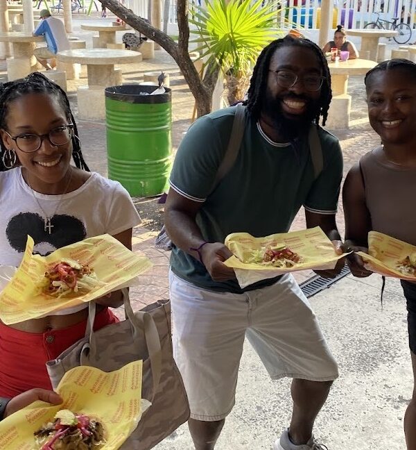 Travelers holding a plate of Yucatecan salbutes during a Cancun Taco Tour