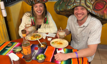 Two travelers eating tacos al pastor and enjoying margaritas on a Cancun Taco Tour