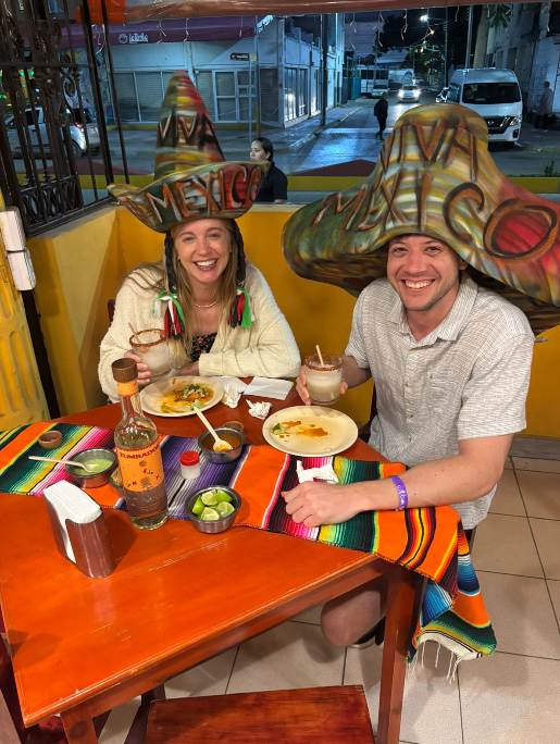 Two travelers eating tacos al pastor and enjoying margaritas on a Cancun Taco Tour