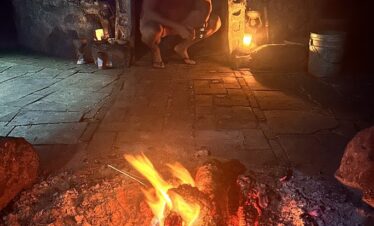 Temazcal fire and hot stones ritual at night with couple inside Mayan ceremony
