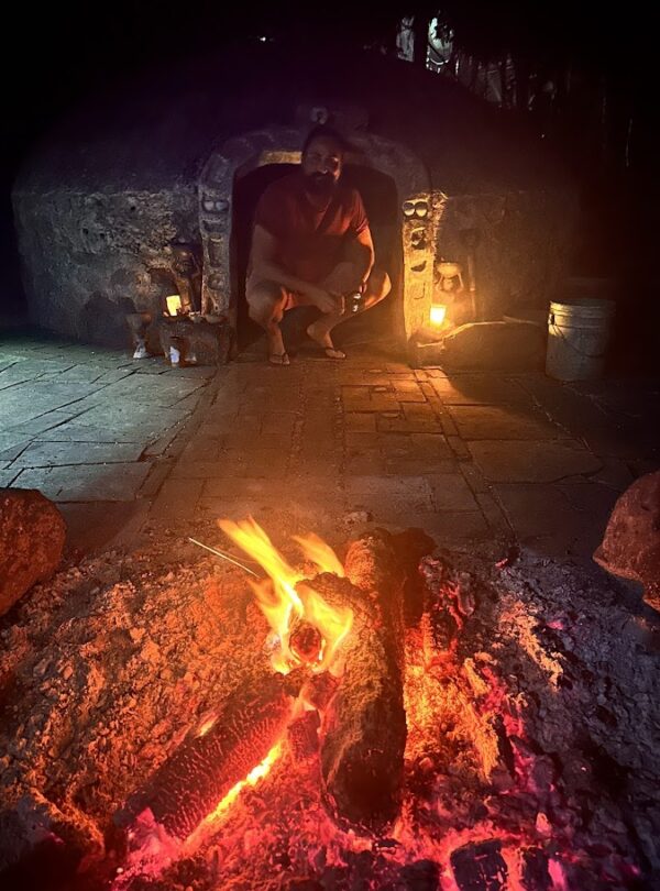 Temazcal fire and hot stones ritual at night with couple inside Mayan ceremony