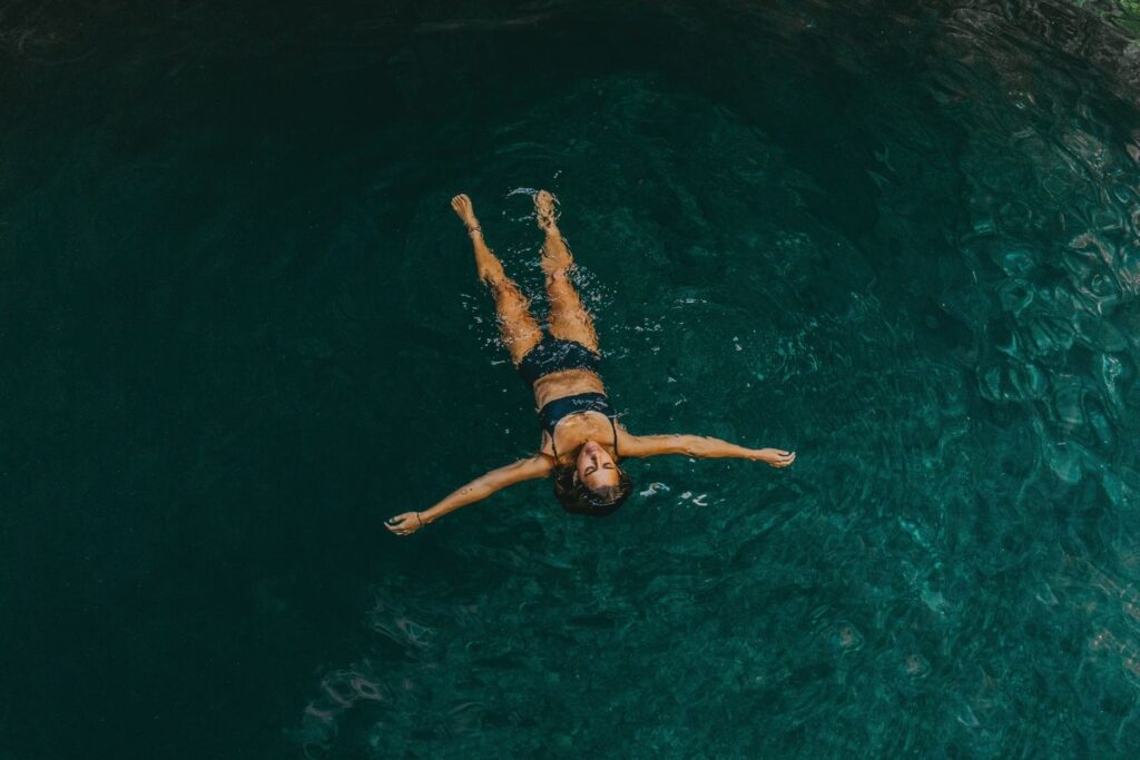 Woman floating in cenote water surrounded by nature Riviera Maya experience