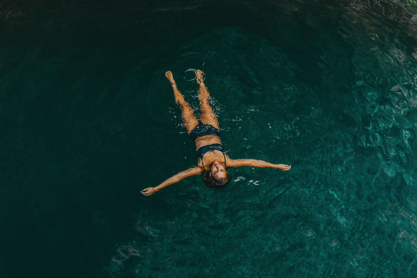Woman floating in cenote water surrounded by nature Riviera Maya experience
