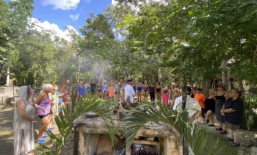 Mayan spiritual guide blessing participants in semicircle before temazcal ceremony in Riviera Maya