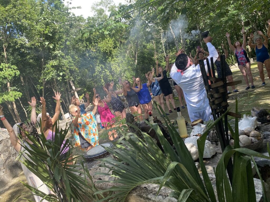 Mayan temazcal ceremony participants raising hands to the four cardinal directions before ritual