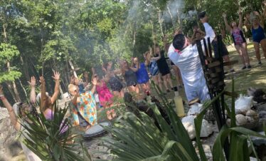 Mayan temazcal ceremony participants raising hands to the four cardinal directions before ritual
