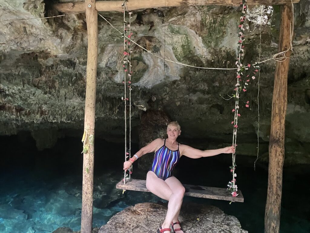 Woman smiling on rustic swing with cenote in background Riviera Maya