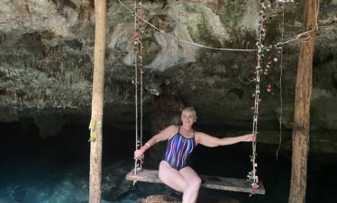 Woman smiling on rustic swing with cenote in background Riviera Maya
