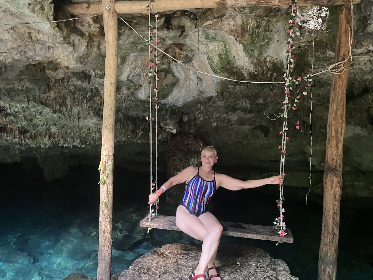Woman smiling on rustic swing with cenote in background Riviera Maya